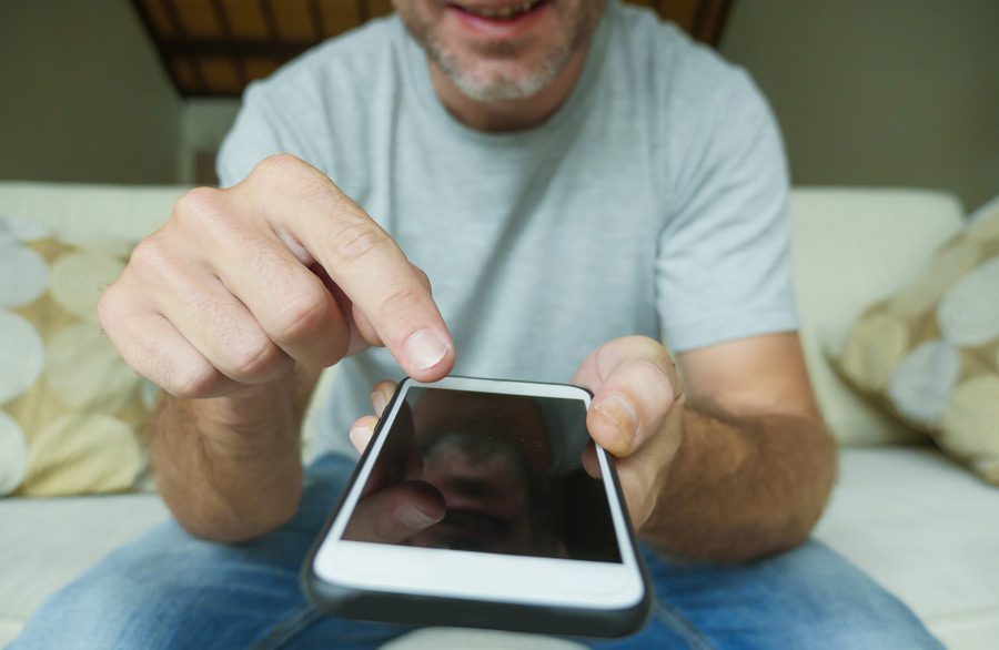 A man tapping on his smartphone screen.